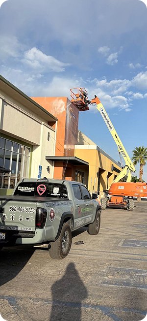 Fieldtech Integrated Pest Solutions branded truck parked at a commercial building job site in California with a cherry picker boom lift performing exterior pest control work
