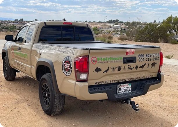 Fieldtech Integrated Pest Solutions branded truck rear view in Apple Valley CA desert showing pest icons website and phone numbers 800-805-5758 and 909-212-3980