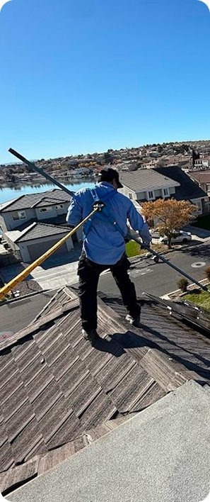 Fieldtech pest control technician working on a residential rooftop with an extension pole performing high-access exterior pest control treatment in California